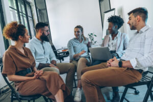 Professionals sit in a circle discussing ideas, creating a space of psychological safety.